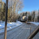 Donald Rigging trucks traveling up a hill in the snow while transporting a compressor.