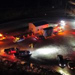Two Western Star trucks, a Kenworth truck, a bed truck, and a 12-line platform trailer prepare to transport their oversized loads overnight.